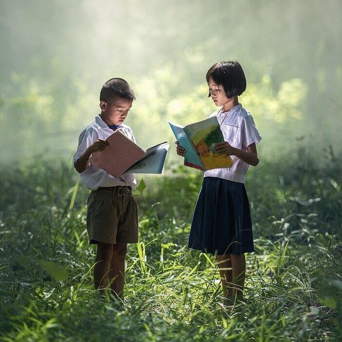 2 children reading books in the forest